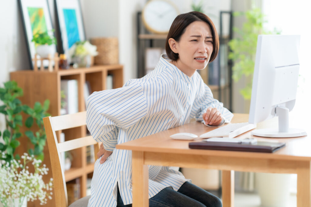 デスクワーク中に腰痛を感じている男性