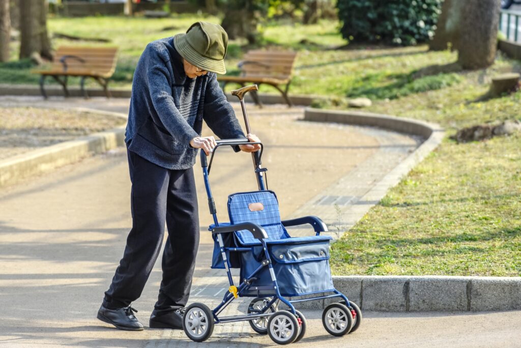 シルバーカー(手押し車)を押して公園を散歩する高齢の女性