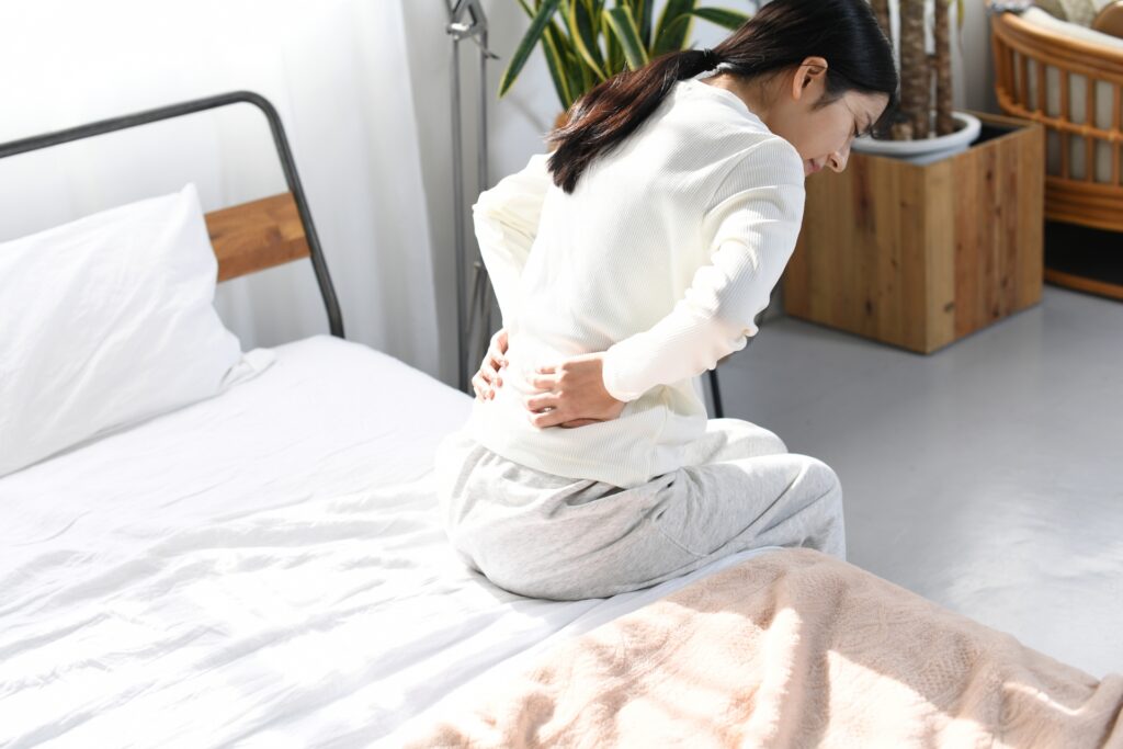 ベッドの上で腰に手を当てる女性