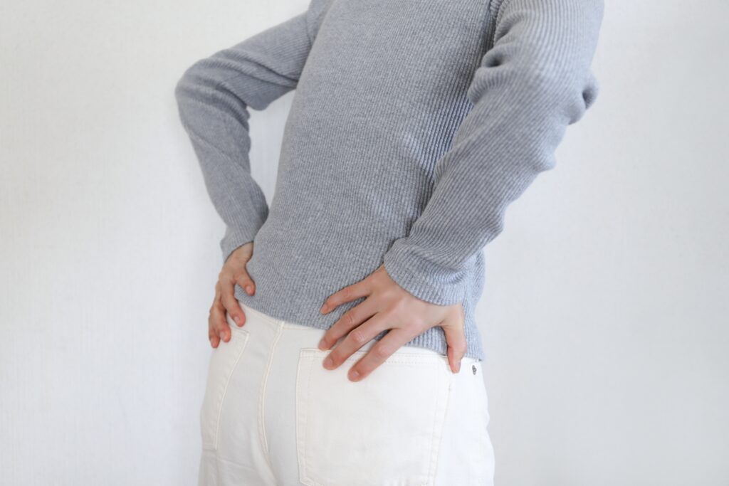腰の片側を手で押さえる女性
